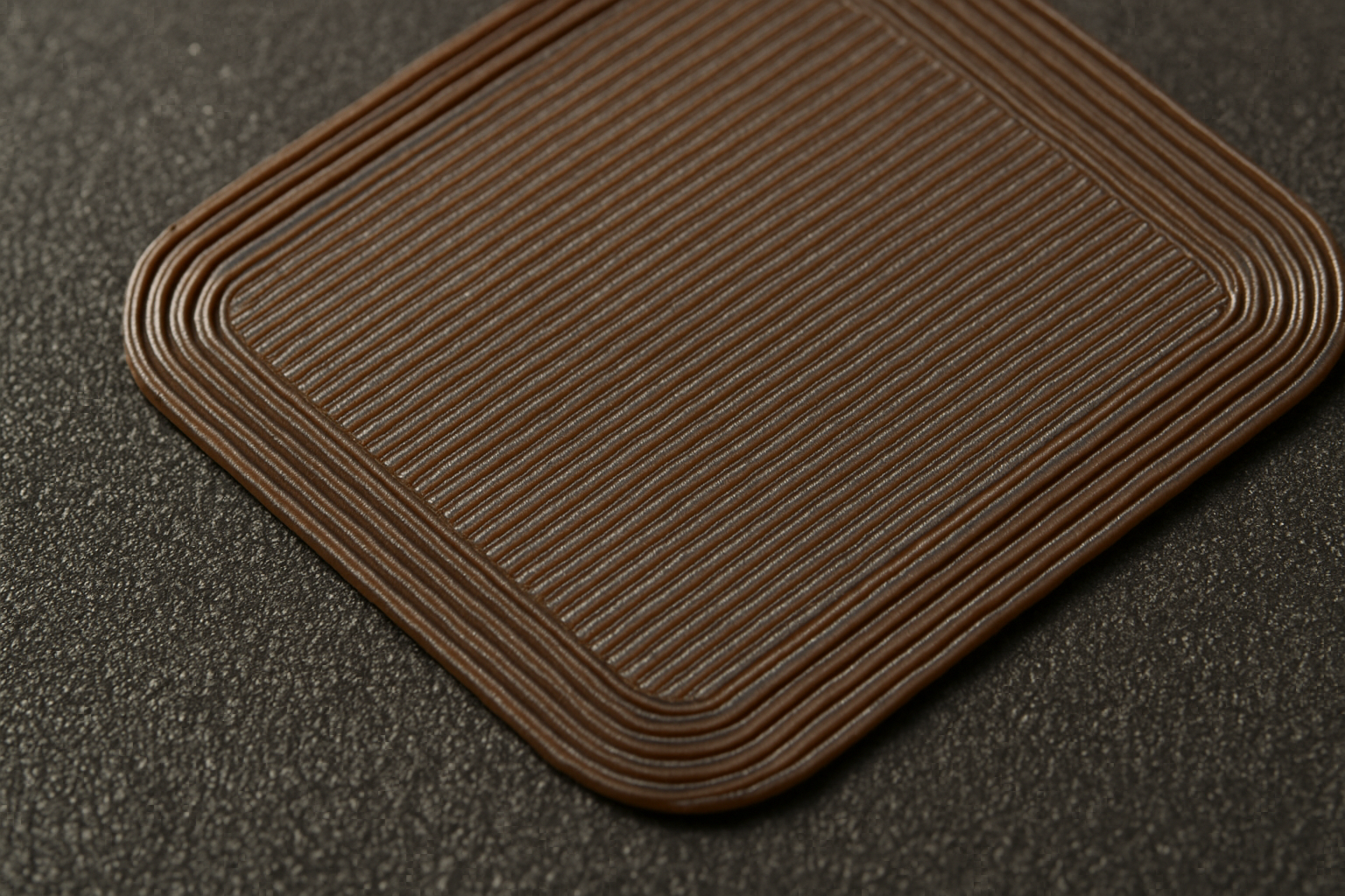 A close-up of a perfect 3D printed first layer on a textured PEI build plate.