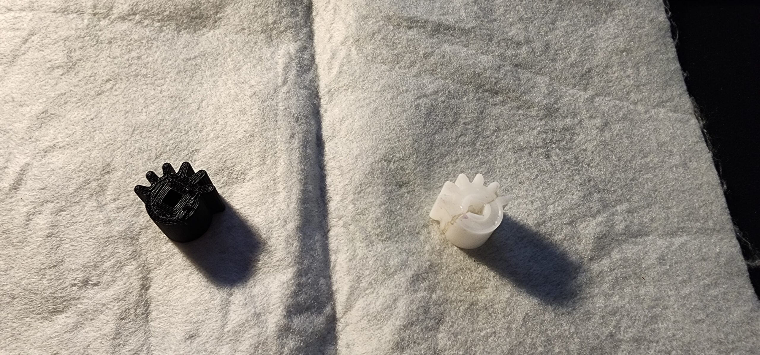 Black 3D-printed Halloween mechanism gear beside Kevin’s damaged white original gear